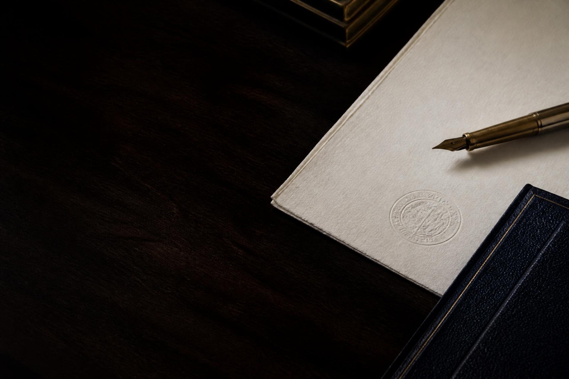 Documento de papel fino, sello y pluma sobre un escritorio de madera